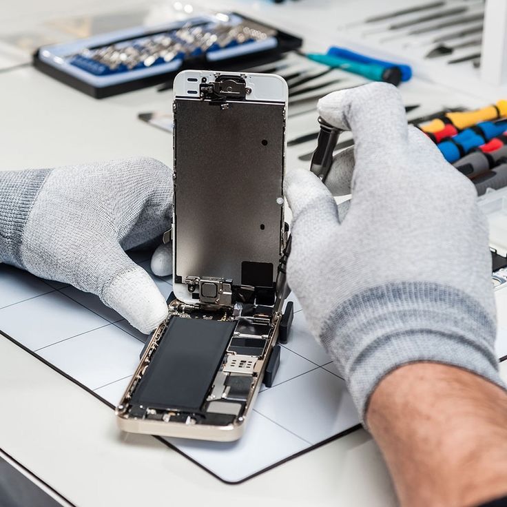 Técnico com luvas trabalhando na manutenção de um celular